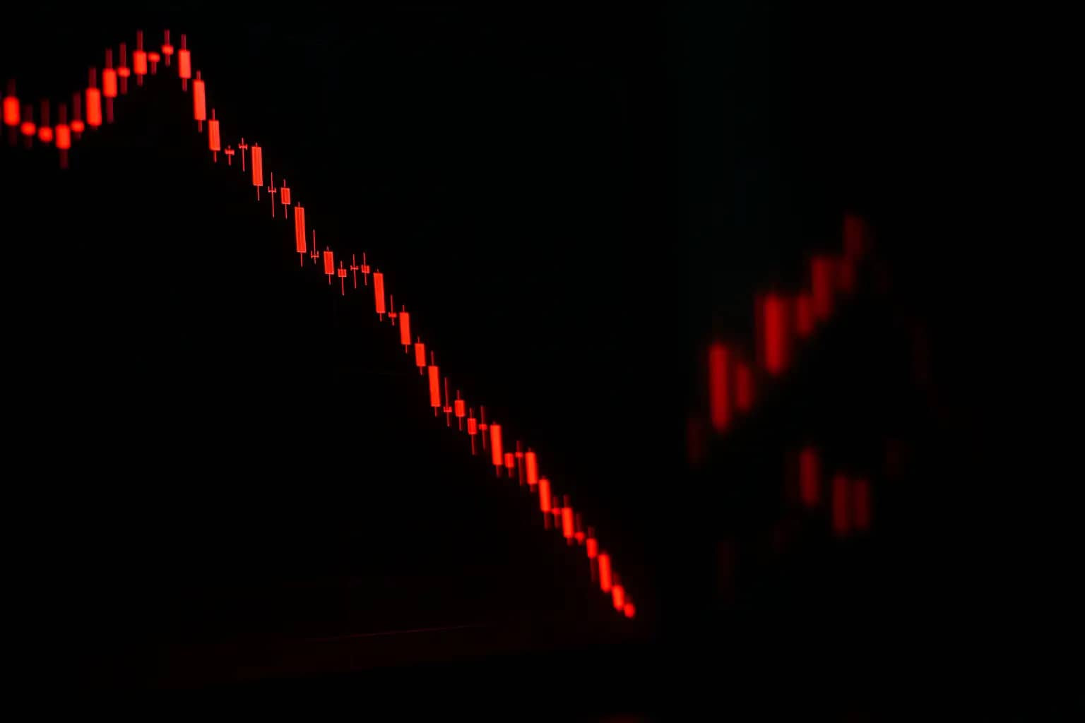 A red declining price chart on a digital trading screen with Bitcoin symbol visible