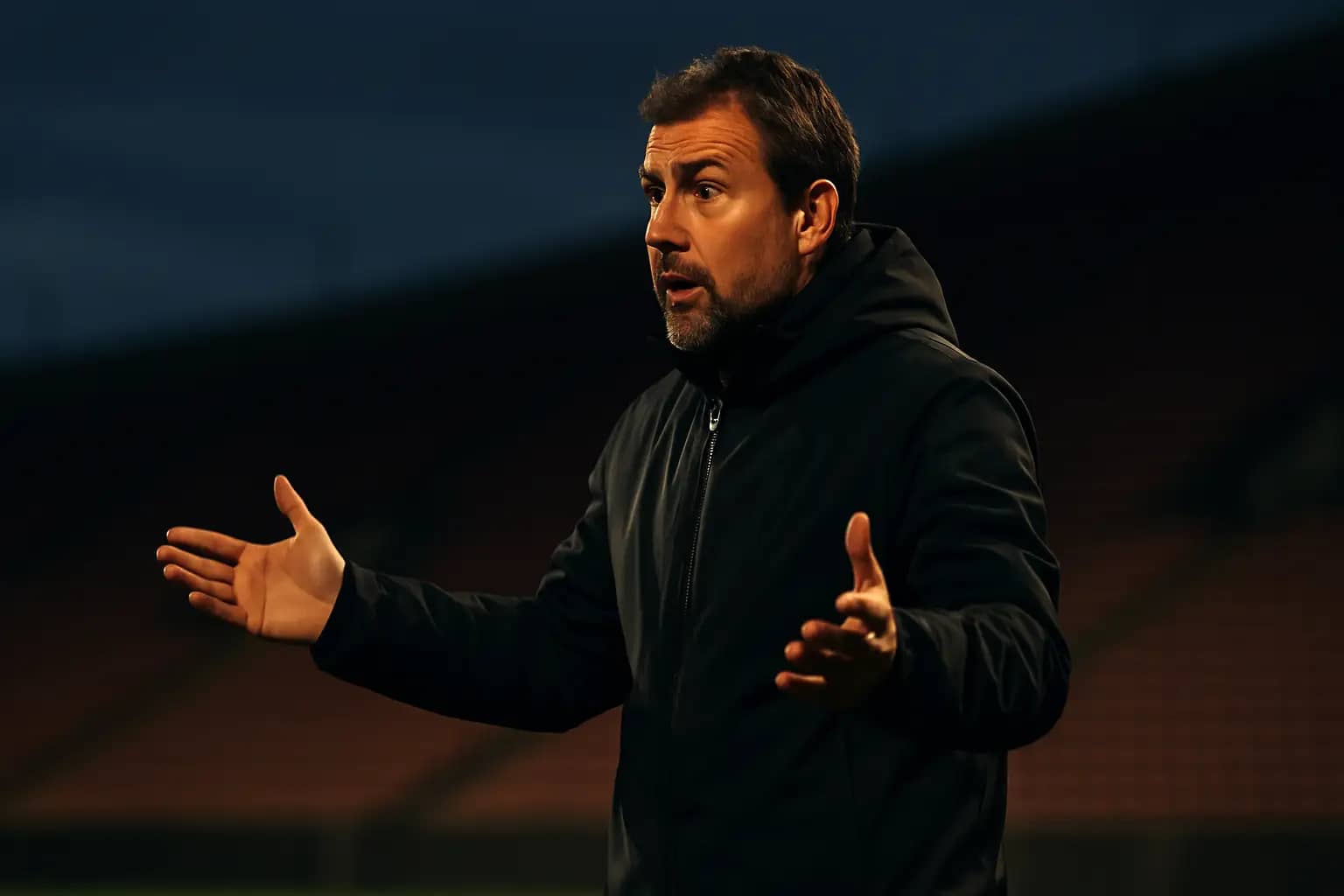 A soccer coach gesturing on the touchline during an international match